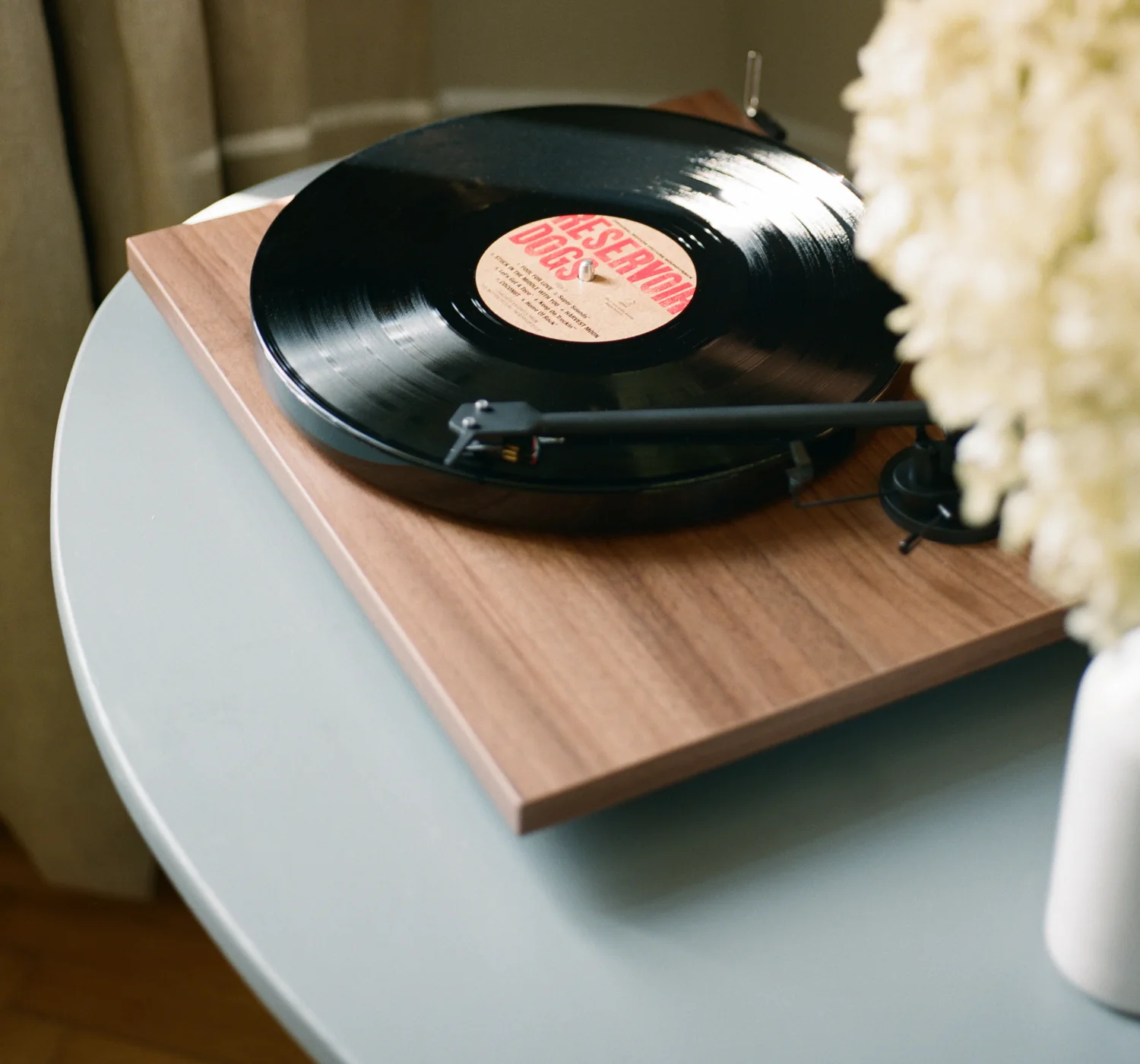 Pro-Ject platespiller i valnøtt med vinylplate på et lite stuebord